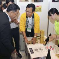 A bottle of Kizunamai sake is shown to guests during a promotional event Wednesday in Tokyo. Part of the proceeds from its sales will be donated to support disaster-hit areas. Sake to support Japan's disaster-stricken areas unveiled at Tokyo event