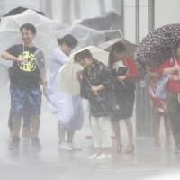 Pedestrians are plastered by rain while waiting to cross a street during a typhoon in western Japan last month. 'Very strong' typhoon projected to hit Honshu on Tuesday