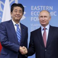 Prime Minister Shinzo Abe and Russian President Vladimir Putin shake hands prior to their talks at the Eastern Economic Forum in Vladivostok, Russia on Sept. 10. Putin's unacceptable peace treaty condition