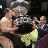 Hakuho receives the Prime Minister’s Cup from Chief Cabinet Secretary Yoshihide Suga on Sunday at Ryogoku Kokugikan. Hakuho won the basho with a 15-0 record. Hakuho wins battle of yokozuna to finish Autumn Basho with 15-0 record