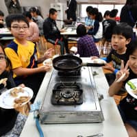 Fifth graders at Oji Daigo Elementary School eat pork fried with liquid shiokōji (traditional Japanese condiment). | YOSHIAKI MIURA