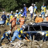 Rescue personnel conduct a search for missing people on July 9 in the town of Kumano, Hiroshima Prefecture, hit by landslides triggered by torrential rain. | KYODO
