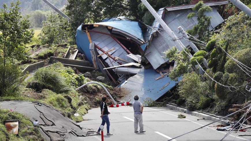 A house lies in ruins across a road in the town of Atsuma, where 36 residents were killed by landslides caused by a magnitude 6.7 quake that hit Hokkaido on Sept. 6. | KYODO