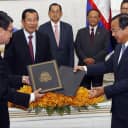 Foreign Minister Taro Kono (left) and his Cambodian counterpart, Prak Sokhonn, exchange documents as Cambodian Prime Minister Hun Sen looks on at a signing ceremony for a $90 million aid pact in Phnom Penh on April 8, 2018.