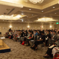 Audience members raise their hands to ask questions during a panel discussion. | ©INTERNATIONAL CONFERENCE FOR WOMEN IN BUSINESS