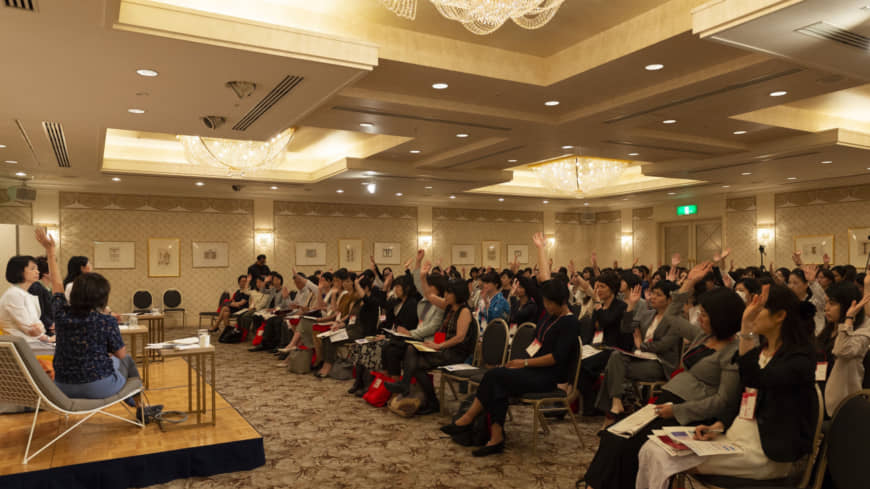 Audience members raise their hands to ask questions during a panel discussion. | ©INTERNATIONAL CONFERENCE FOR WOMEN IN BUSINESS