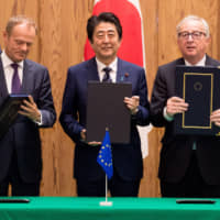 European Council President Donald Tusk, Prime Minister Shinzo Abe and European Commission President Jean-Claude Juncker hold up the signed versions of the economic partnership agreement and the strategic partnership agreement in Tokyo last July. | ETIENNE ANSOTTE, EUROPEAN UNION