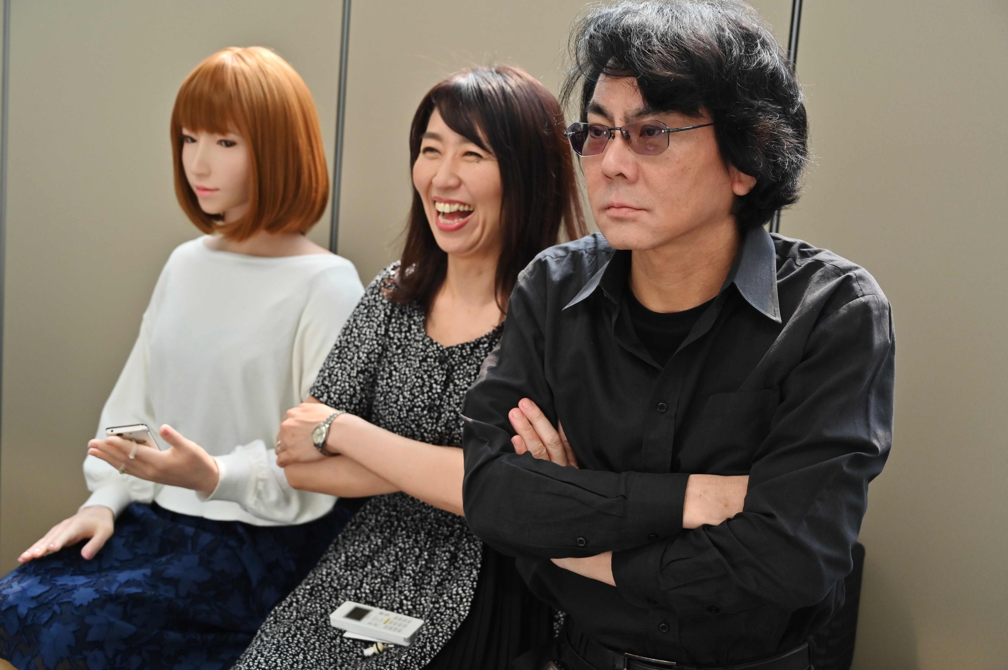 Roboticist Hiroshi Ishiguro (right) and his assistant pose next to one of his robots at his research center in Osaka in June. | AFP-JIJI