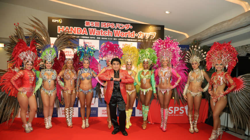 International Sports Promotion Society Chairman Haruhisa Handa (center) and feather-clad Brazilian samba dancers at a dinner following the first day of the ISPS Handa Watch World Cup at Taiheiyo Club Gotemba West in Shizuoka Prefecture on Nov. 4 | ISPS