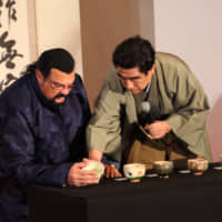 International Sports Promotion Society Chairman Haruhisa Handa teaches actor Steven Seagal how to hold a Japanese teacup at the Hilton Tokyo Odaiba Hotel on Dec. 7. | ISPS