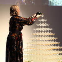 Tindall pours Champagne into an illuminated pyramid of stacked glasses during the talk show. | ISPS