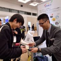 A high school student exchanges his business card with a company representative during a Student Ambassador Program workshop at Pacifico Yokohama. | YOSHIAKI MIURA