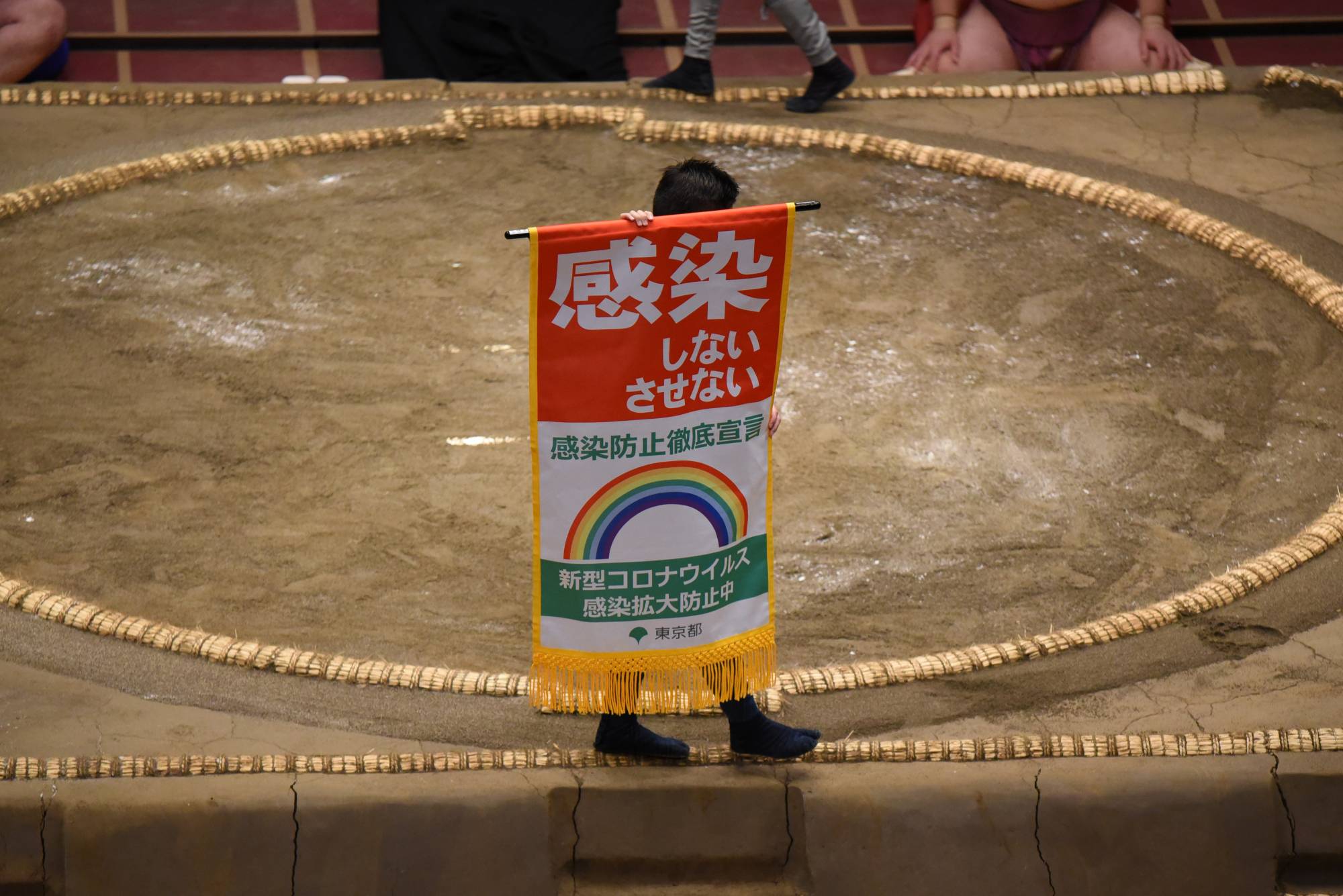 A banner promoting COVID-19 countermeasures is carried around the ring. | DAN ORLOWITZ