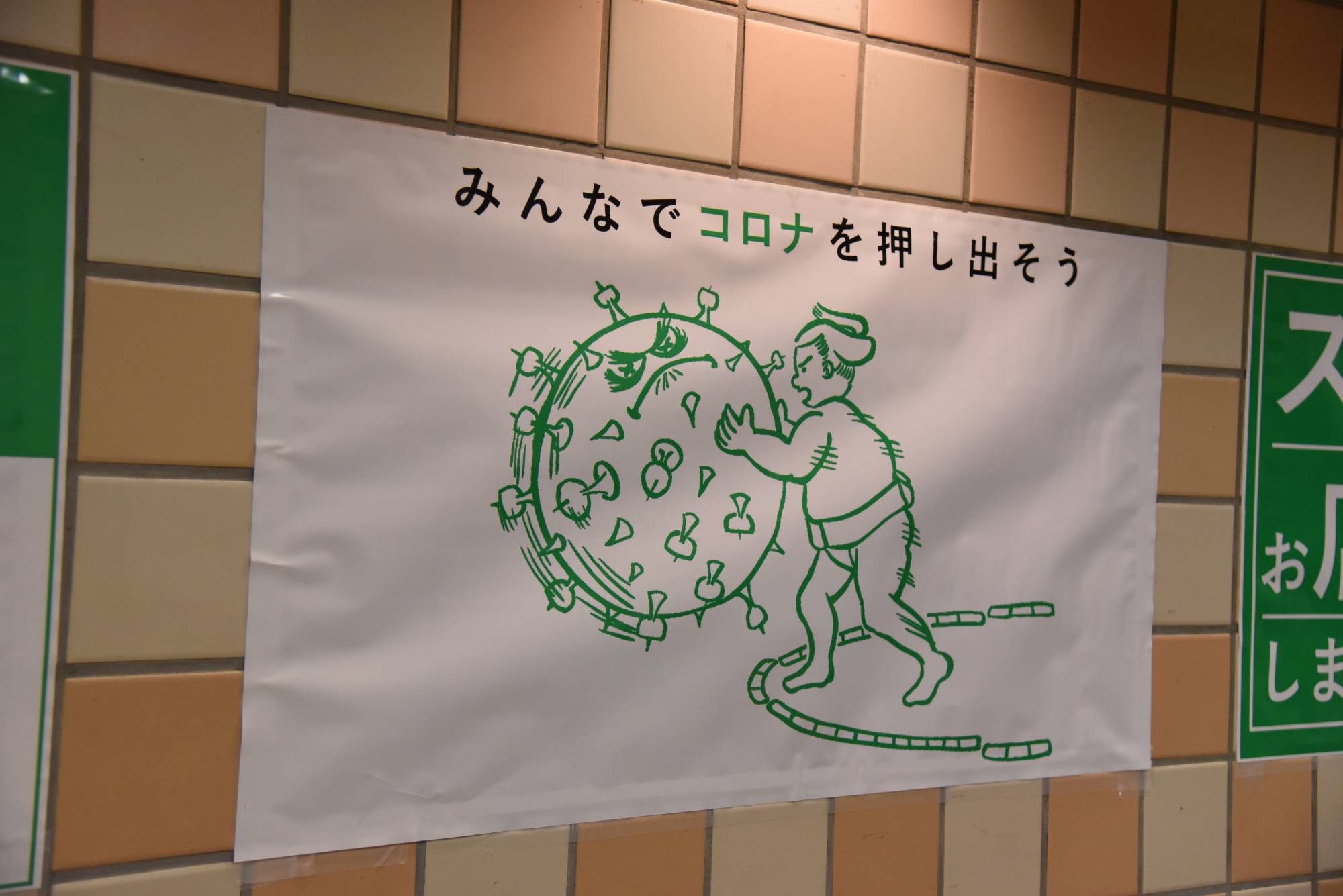 A poster reading 'Let's push out corona together' is displayed in the concourse at Ryogoku Kokugikan. | DAN ORLOWITZ