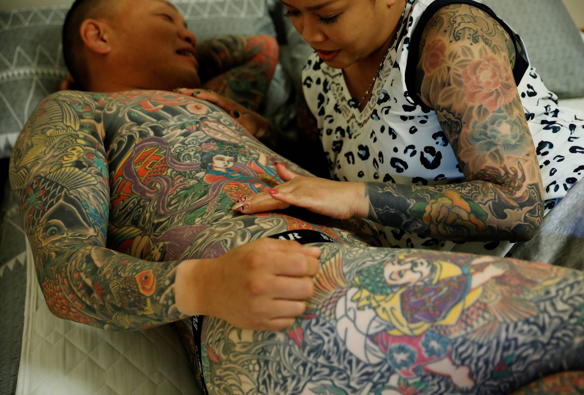 Bookkeeper Mina Yoshimura, 40, who works at her husband Hiroshi Yoshimura's company, touches a new tattoo that he got the same day, at their home in Tokyo on Oct. 2. | REUTERS