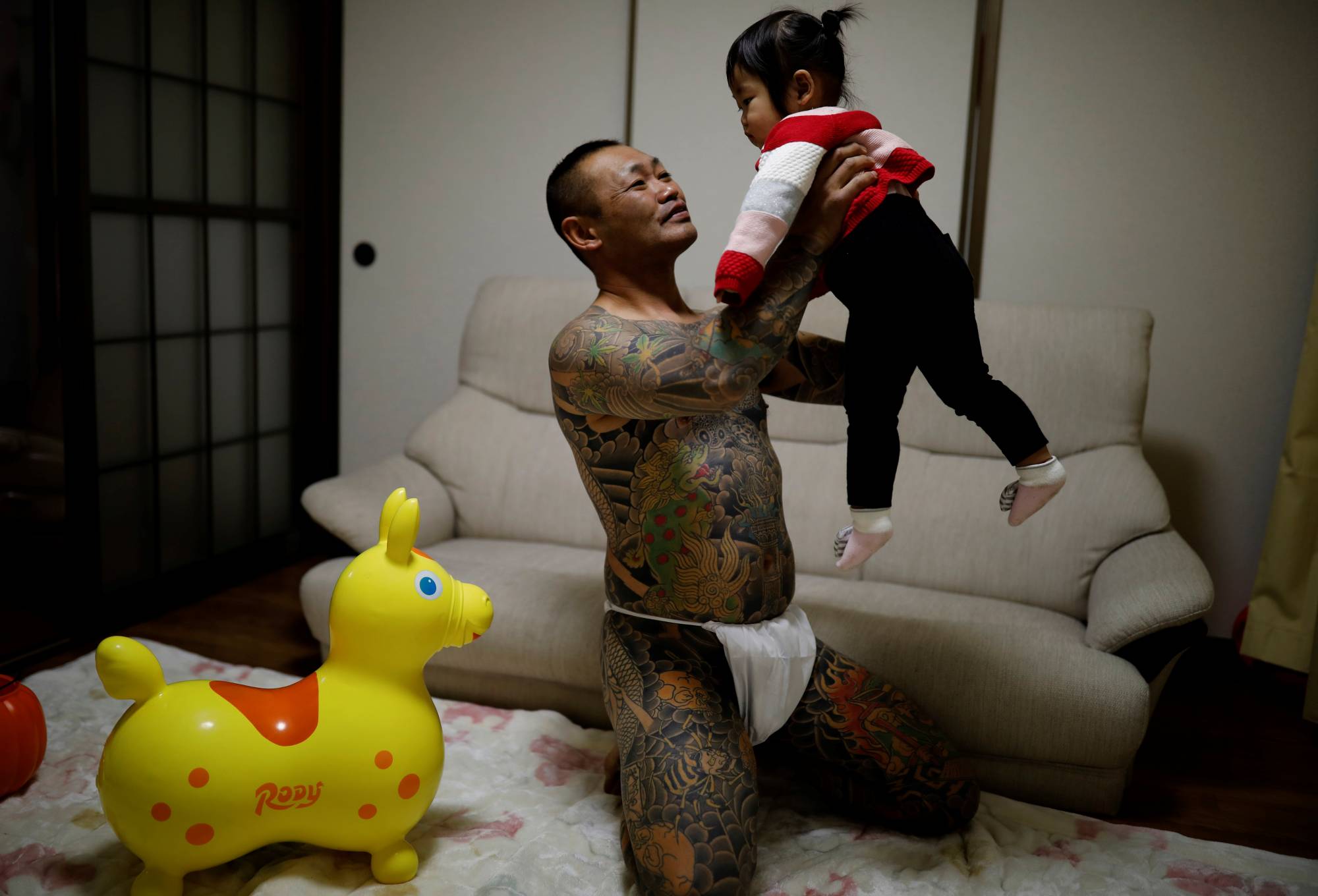 Scrap yard worker Hiroyuki Nemoto, 48, wears a traditional Japanese loincloth as he poses for a photo with his 1-year-old daughter, Tsumugi, at their house in Hitachinaka, Ibaraki Prefecture, in January. | REUTERS