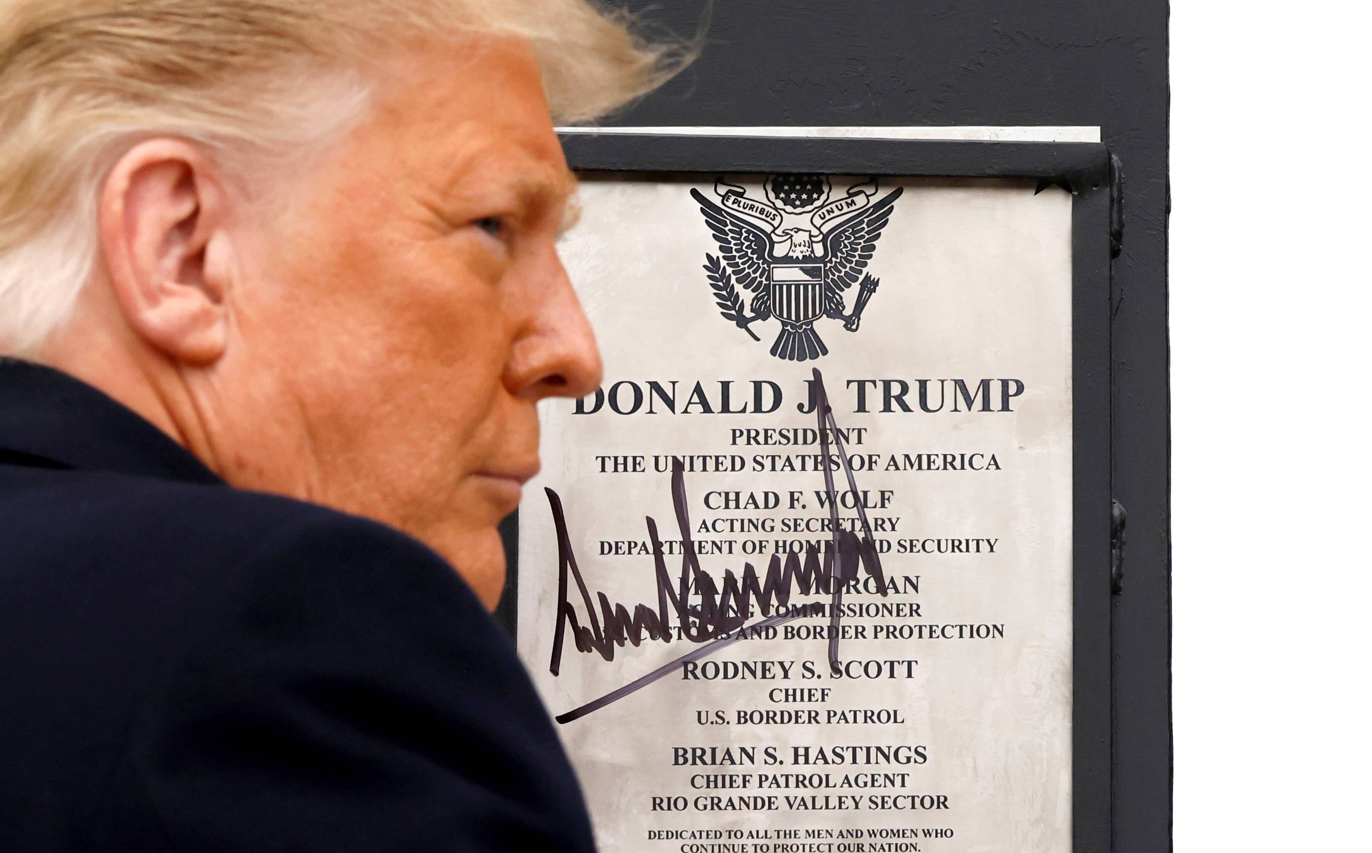 U.S. President Donald Trump signs a plaque placed at the U.S.-Mexico border wall during his visit, in Alamo, Texas, on Tuesday. | REUTERS
