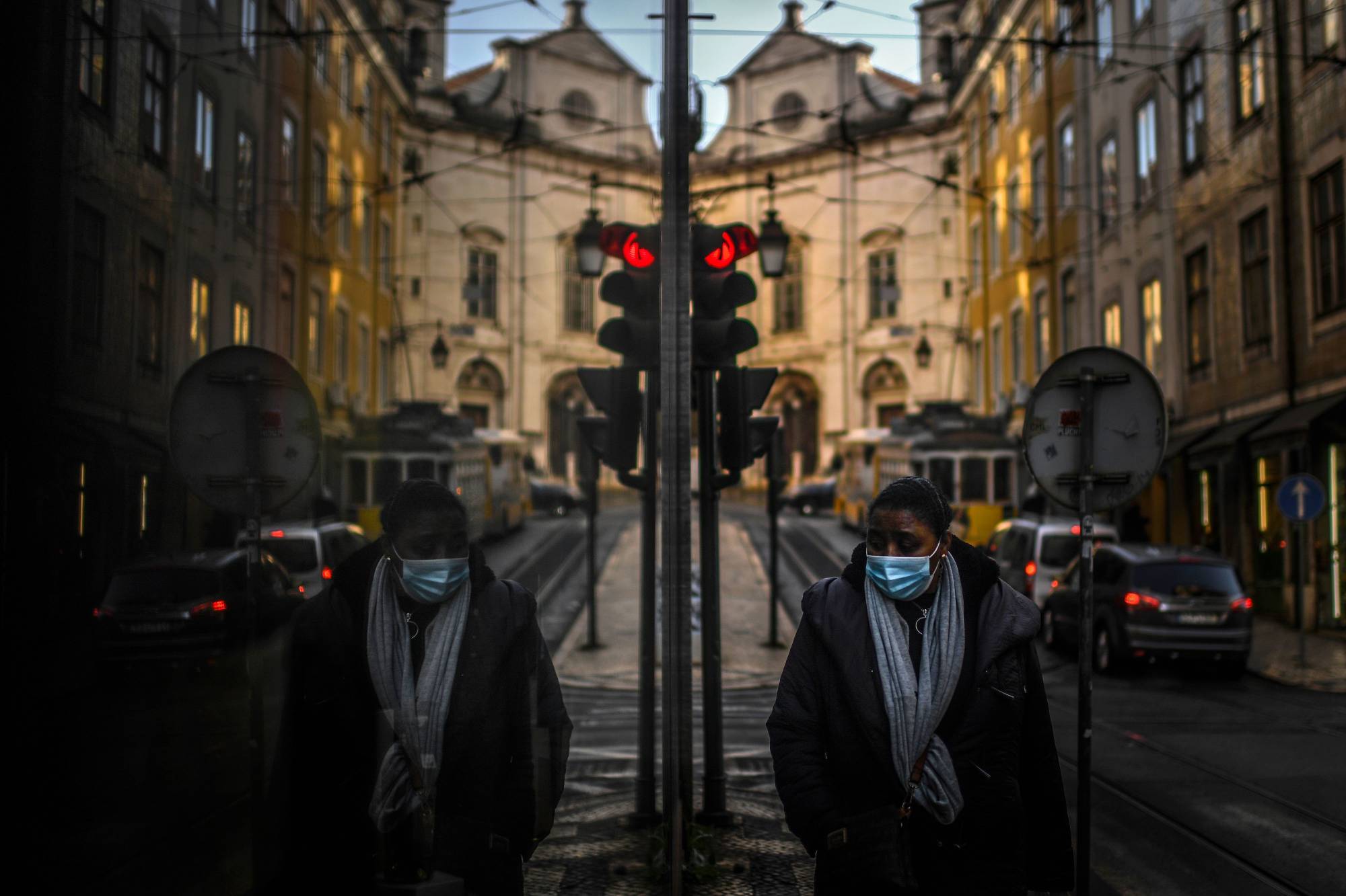 A woman is reflected in a shop window in Lisbon on Friday as Portugal entered a fresh lockdown over a surge in coronavirus cases. | AFP-JIJI