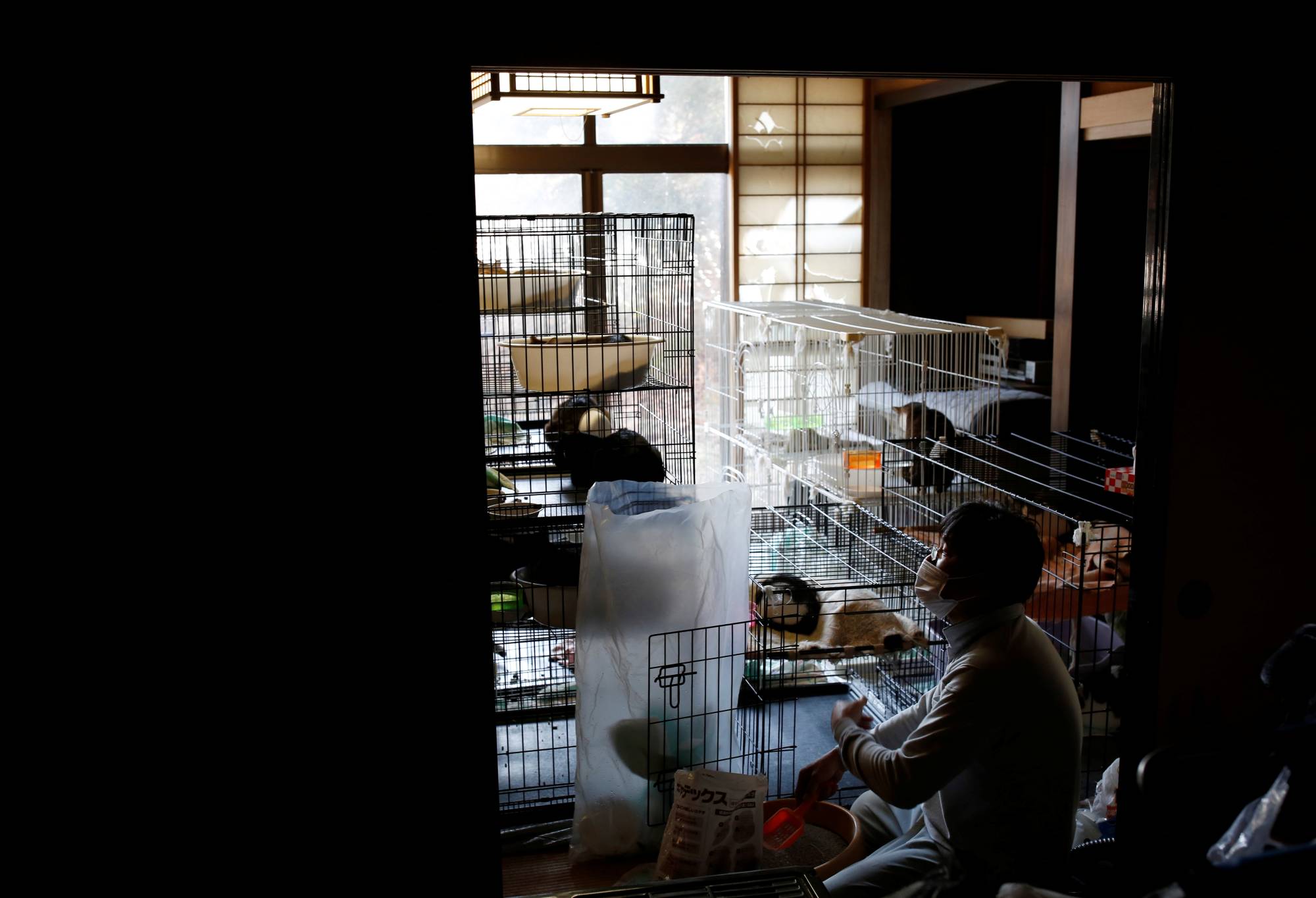 Kato cleans one of the many cages in this two-story home. | REUTERS