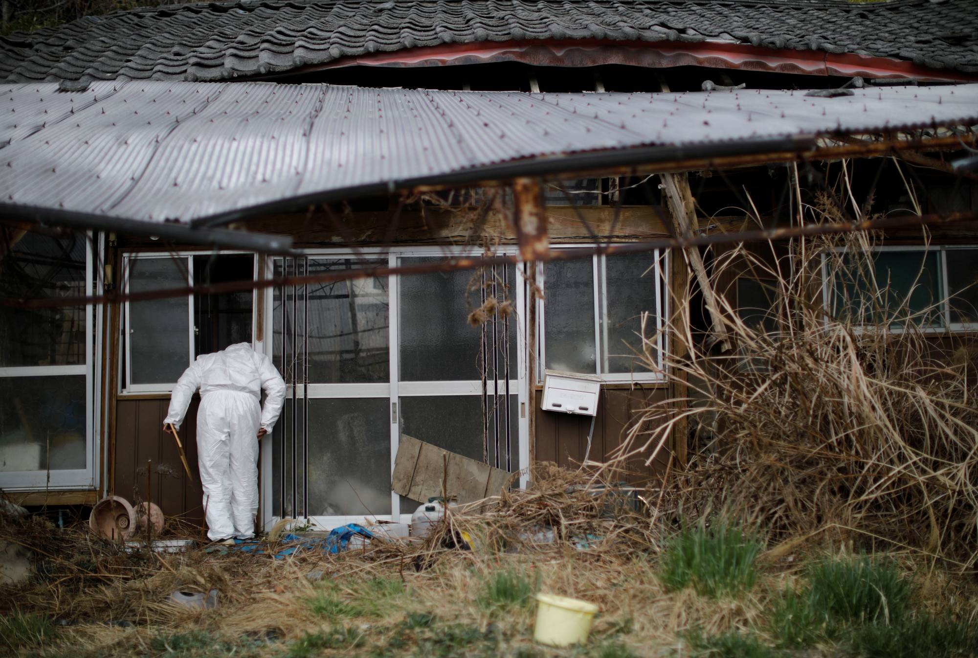 Hisae Unuma looks into the house that she lived in, 2.5 kilometers away from the crippled Fukushima No. 1 nuclear power plant, before being evacuated in March 2011. | REUTERS