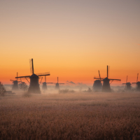 De molens van Kinderdijk in het licht van de ochtendglorie metj een zonsopkomst.