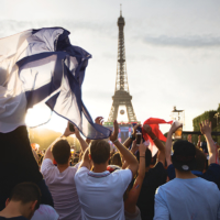People cheer while waving French 'tricolor' flags near the Eiffel Tower on the Champ de Mars in Paris. | ©THOMAS LEFEVRE / MAIRIE DE PARIS