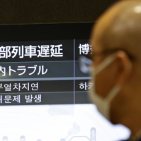 A sign at JR Hakata Station indicates a delay on train services after a 69-year-old Fukuoka man was arrested for setting a fire on a bullet train Monday morning. | KYODO