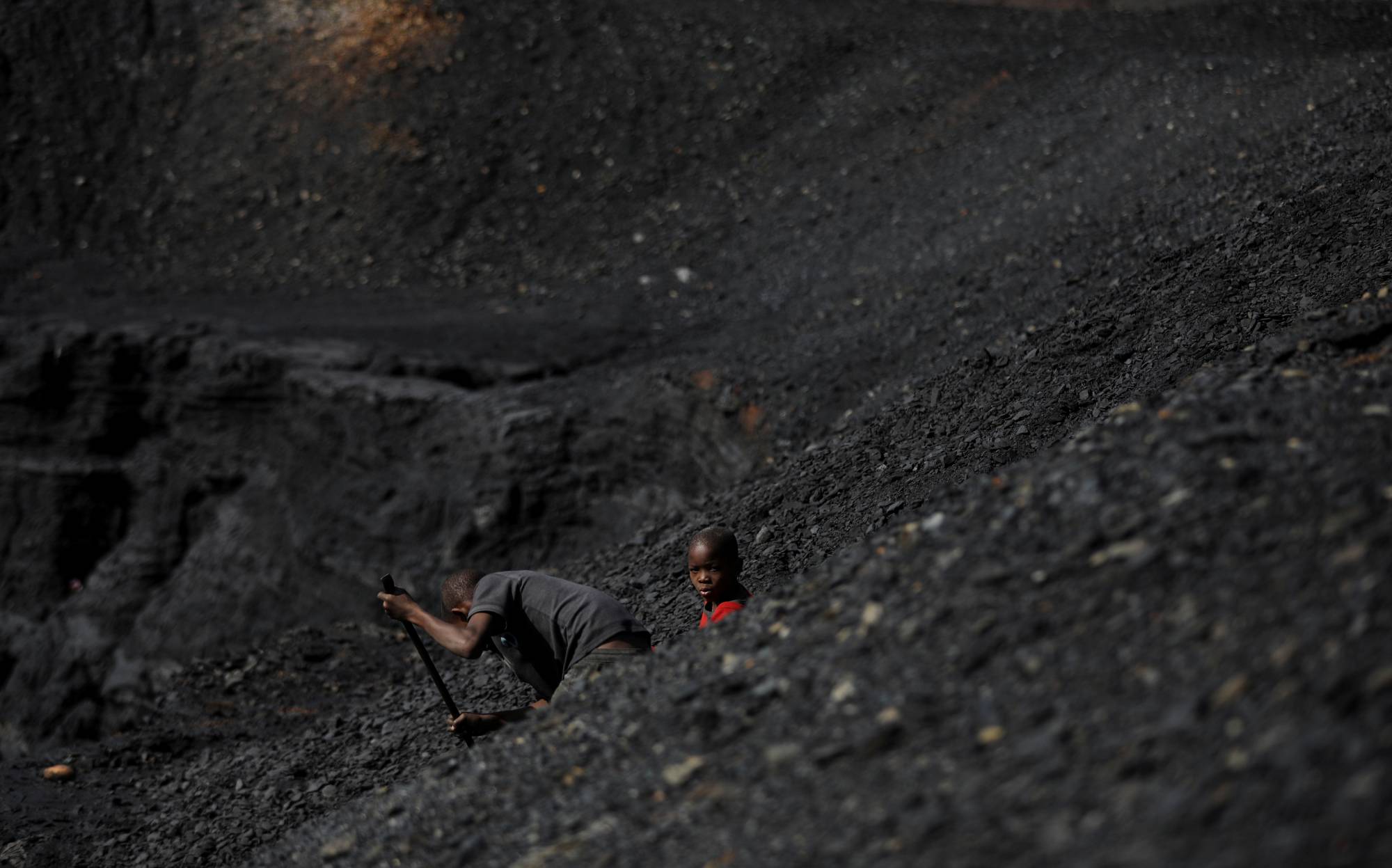 A child collects lumps of coal from a colliery while smoke rises from the Duvha coal-fired power station in Emalahleni.  |  REUTERS 