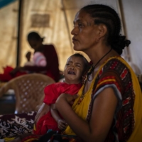 A mother holds her starving daughter at a clinic in Abi Adi, Ethiopia, in May. Hunger got drastically worse in 2020, the U.N. said in July, and a multiagency report estimates up to 811 million people suffered from malnutrition last year. | AP/ VIA KYODO