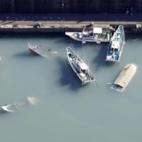 Ships are seen capsized at a port in Muroto, Kochi Prefecture, on Sunday.