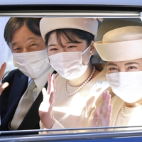 Emperor Naruhito, Empress Masako (right) and their daughter Princess Aiko wave from a car before meeting Emperor Emeritus Akihito and Empress Emerita Michiko for New Year’s greetings on Jan. 1. | KYODO