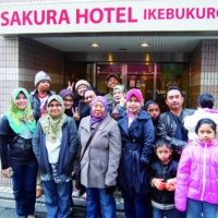 Guests pose for a photo at the entrance of Sakura Hotel Ikebukuro in Tokyo’s Toshima Ward. | SAKURA HOTEL AND SAKURA HOUSE