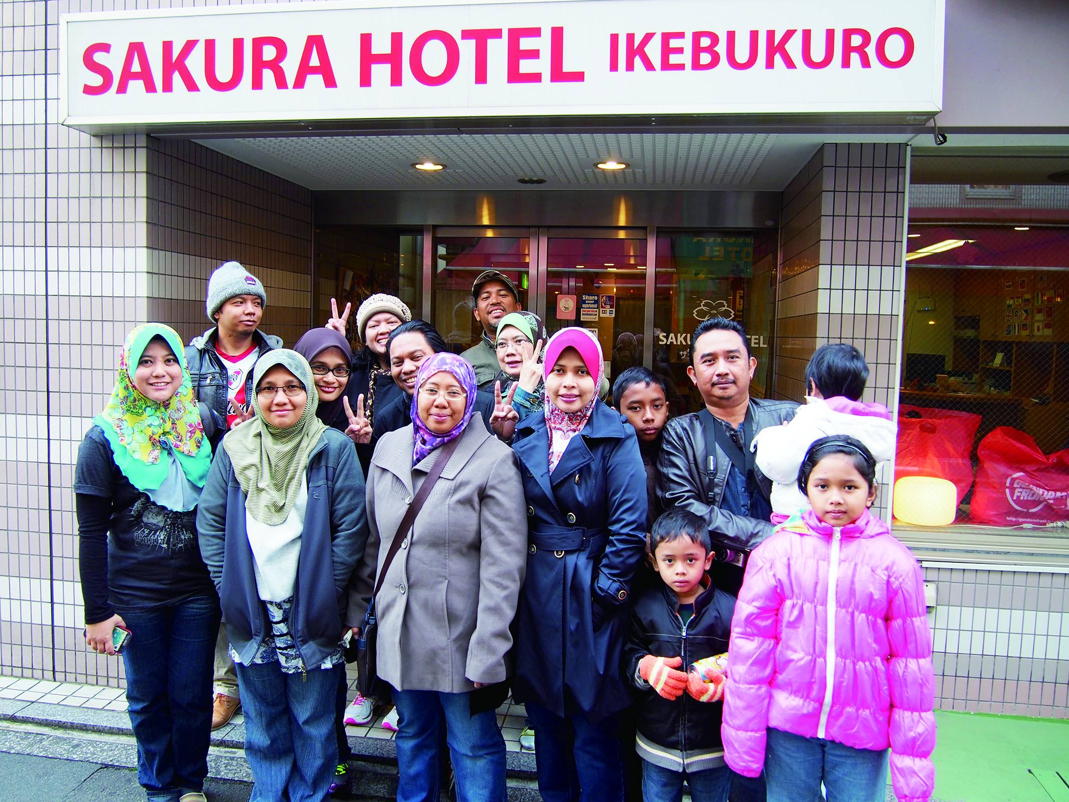 Guests pose for a photo at the entrance of Sakura Hotel Ikebukuro in Tokyo’s Toshima Ward. | SAKURA HOTEL AND SAKURA HOUSE