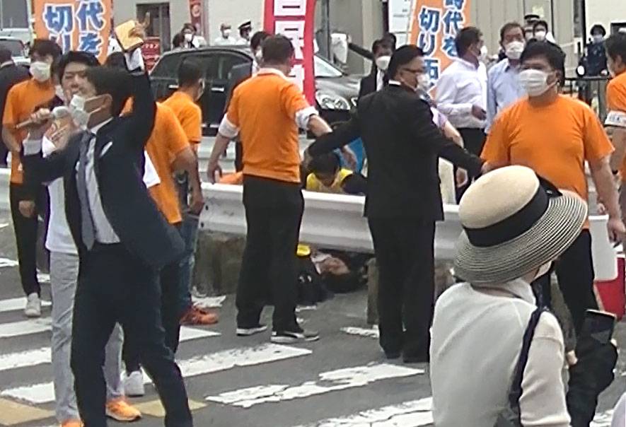 Abe (center) lies on the ground in Nara after being shot on Friday. | KYODO