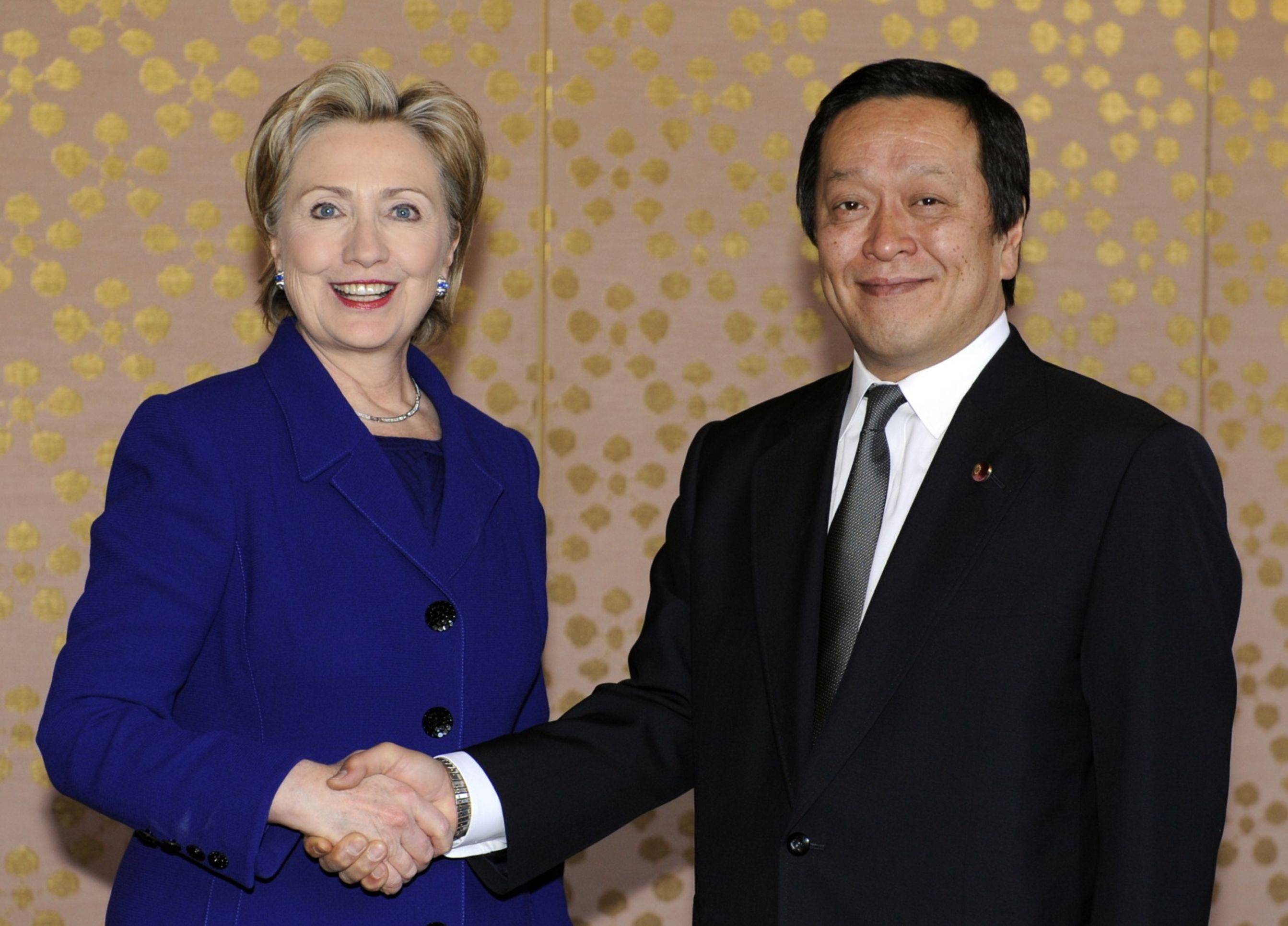 Then-U.S. Secretary of State Hillary Clinton shakes hands with Yasukazu Hamada, Japan's defense minister at the time, prior to their meeting at the Iikura Guest House in Tokyo in February 2009. | POOL / VIA BLOOMBERG