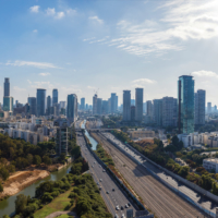 Aerial view of Tel Aviv skyline with urban skyscrapers at sunset and cars on Ayalon highway, Israel