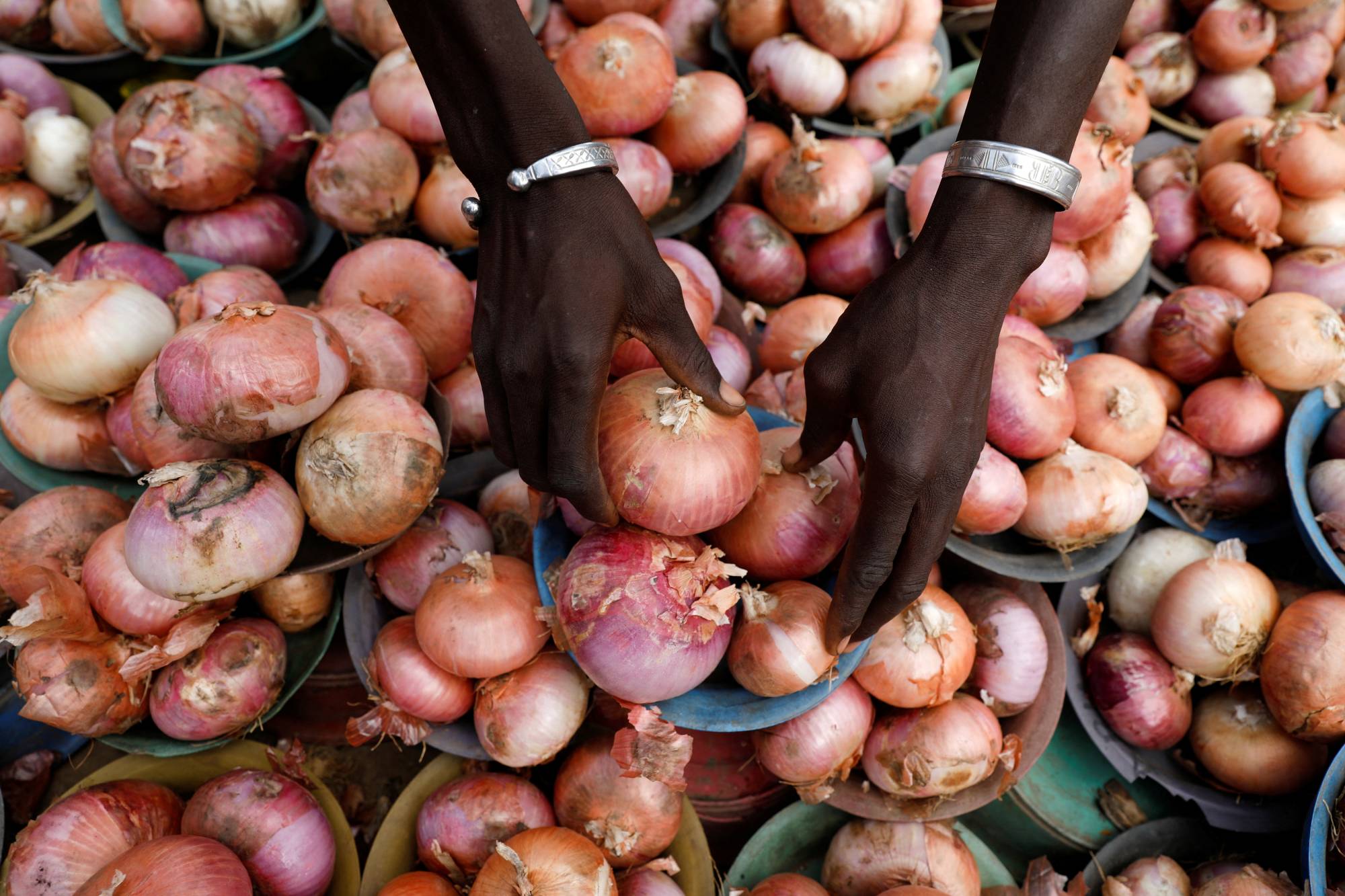 A vendor arranges onions for sale at a market in Lagos in May. Anecdotal evidence suggests that among the Nigerian middle class, emigration has spiked, fueled by a slumping currency, worsening insecurity, spiraling inflation and corruption. | REUTERS