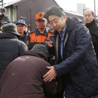 Abe consoles a resident of Itoigawa, Niigata Prefecture, on Jan. 11, 2017, after a blaze destroyed more than 140 structures. | KYODO