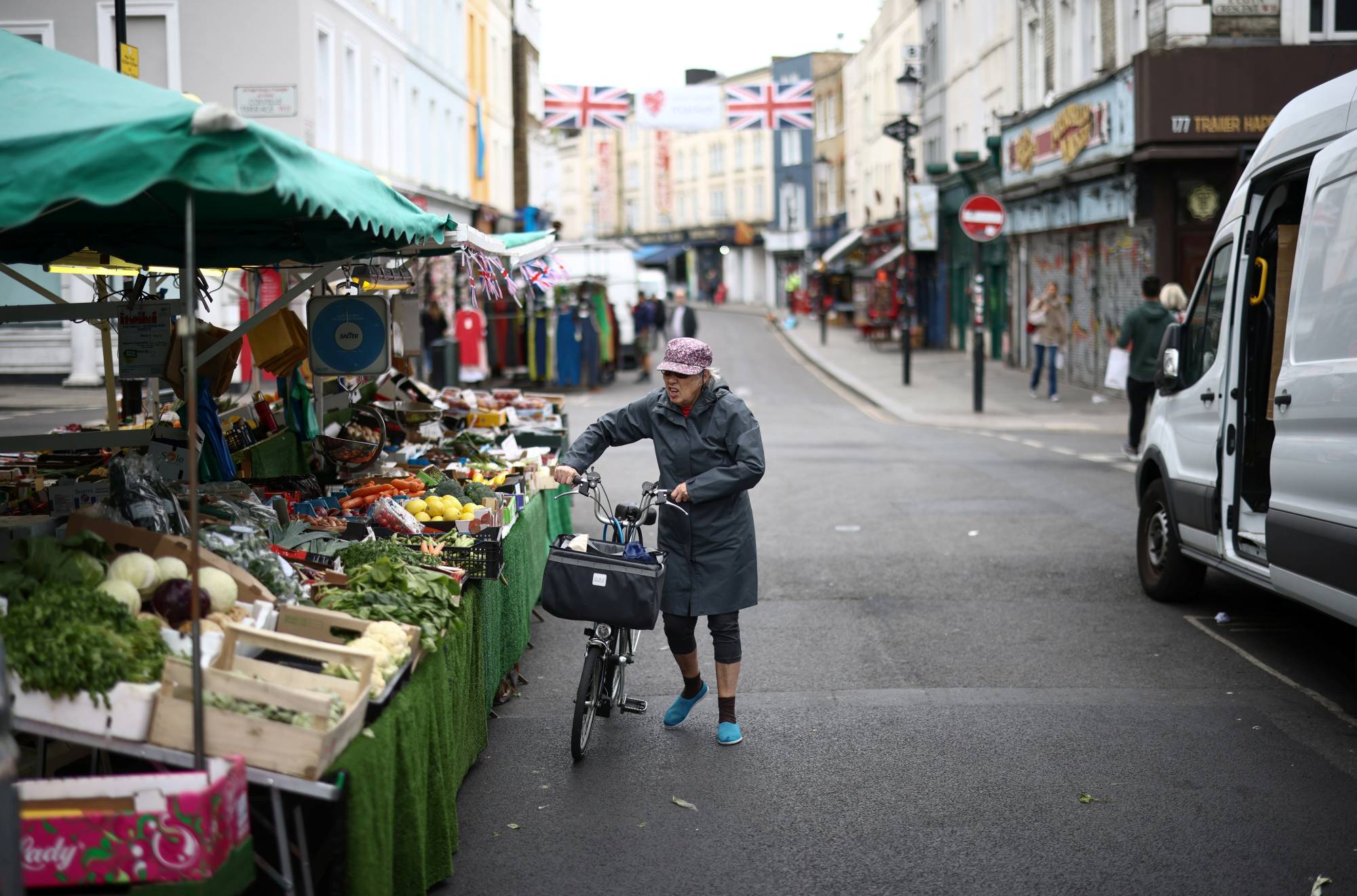 A customer views produce at a market stall on Portobello Road in London. | REUTERS