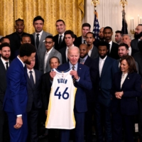 U.S. President Joe Biden is presented with a jersey from members of the reigning NBA champion Warriors during their visit to the White House in Washington on Tuesday. | AFP-JIJI