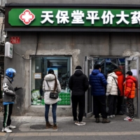 People line up to buy medicine at a drug store in Beijing on Dec. 9. | AFP-JIJI