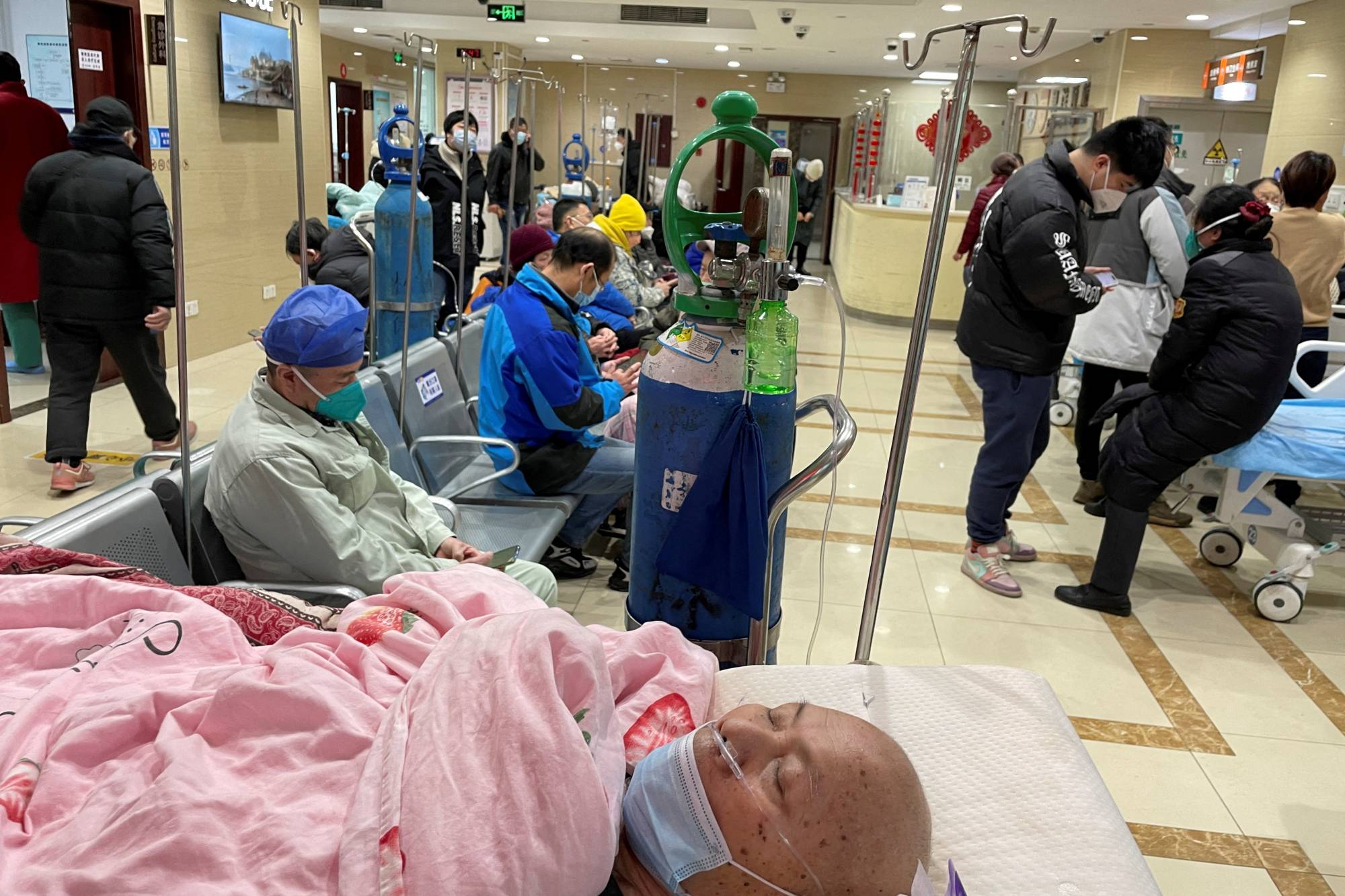 A patient lies on a bed in the emergency department of a hospital in Shanghai earlier this month as China deals with a large wave of coronavirus cases. | REUTERS