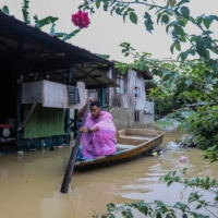 A man paddles a boat next to a partially submerged house after flooding in Kuala Terengganu, Malaysia, on Dec. 21. | REUTERS