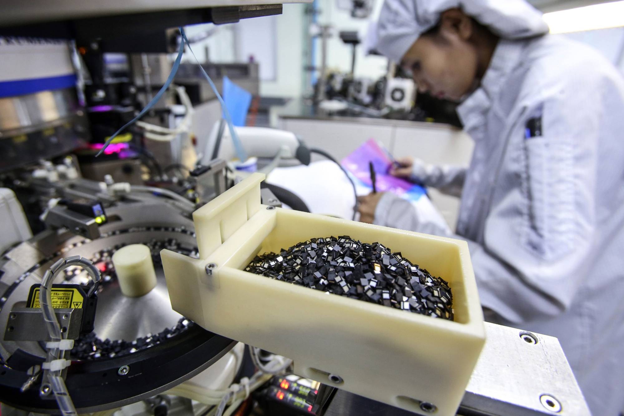 Semiconductor chips sit in a container on the production line at the Hana Microelectronics plant at the Hi-Tech Industrial Estate in Thailand. | BLOOMBERG