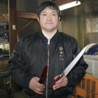Terukazu Takamura, president of the Takamurahamono factory in Echizen, Fukui Prefecture, holds Echizen Uchihamono forged knives on Dec. 16. | KYODO
