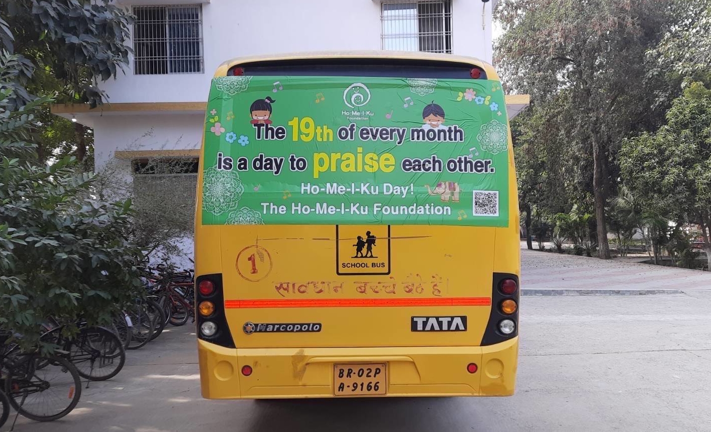 A school bus in India sports an ad on the back urging people to praise each other every month. | SPIRAL UP CO. 