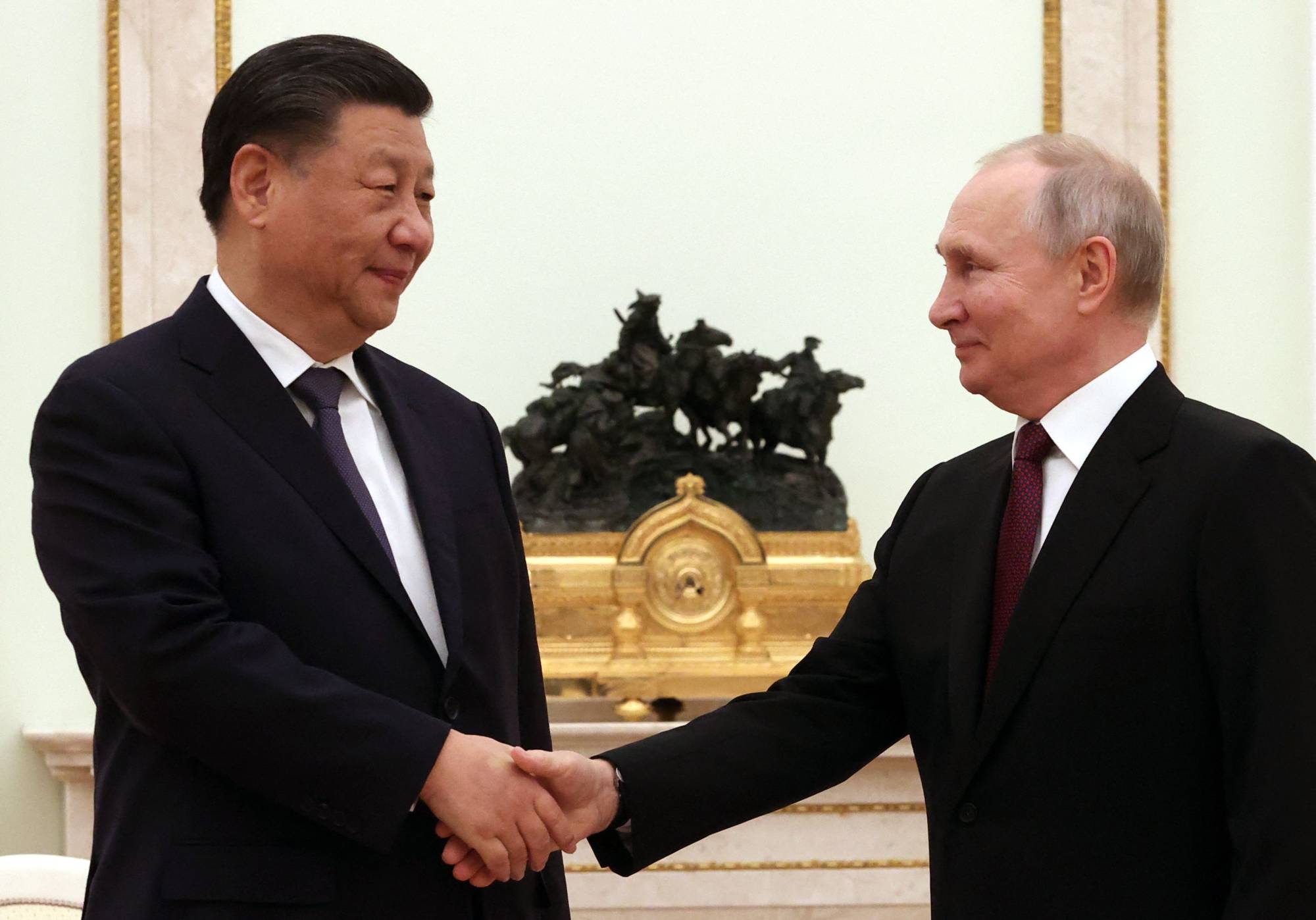 Chinese leader Xi Jinping shakes hands with Russian President Vladimir Putin at the Kremlin in Moscow on Monday.   | SPUTNIK / VIA AFP-JIJI
