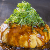 Mouth-watering okonomiyaki, chock-full of vegetables, sits atop Chinese-style noodles.