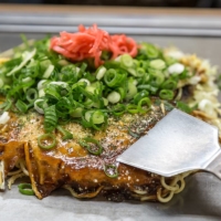 Hiroshima-style okonomiyaki (savory Japanese meat and vegetable pancake) is a Hiroshima staple. | GETTY IMAGES