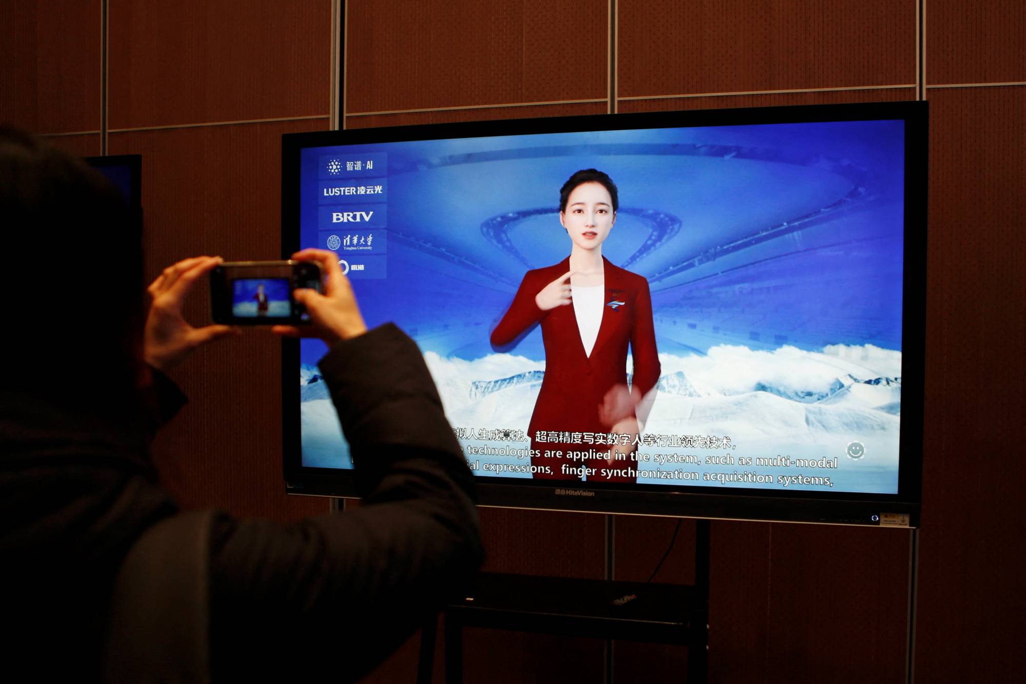 A journalist documents a screen displaying a digital sign-language system run by an artificial intelligence system, during a media tour to the Beijing Academy of Artificial Intelligence in Beijing in February last year. | REUTERS